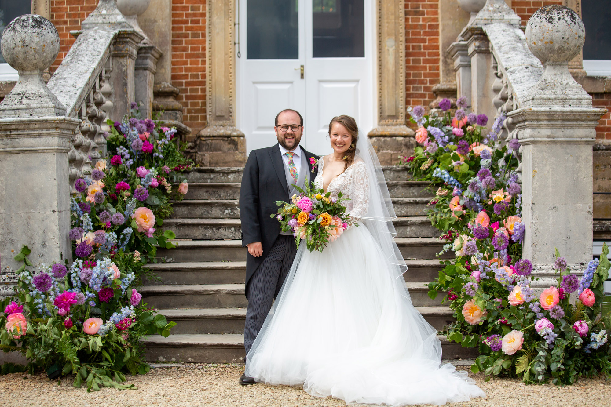 Crowcombe Court steps decorated with summer flowers for a beautiful photo of a groom and bride. Image by Martin Dabek Photography